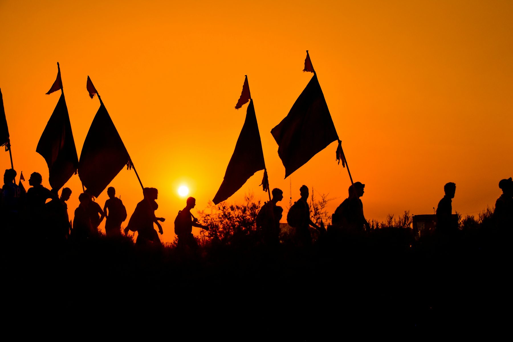 Pilgrims walking with flags at sunset